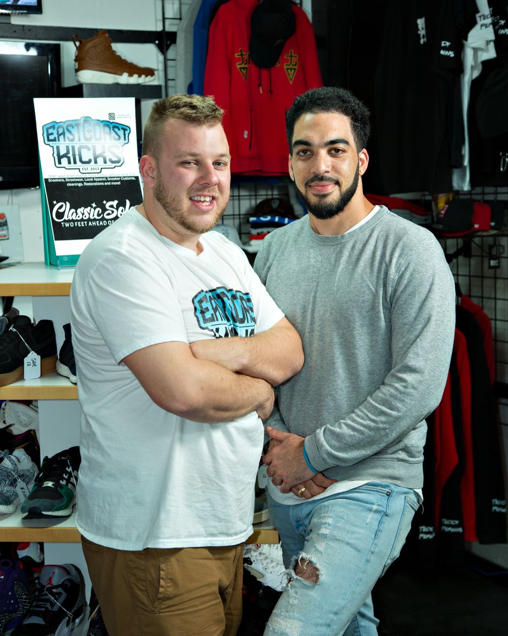 Two men pose with their arms crossed in a store.