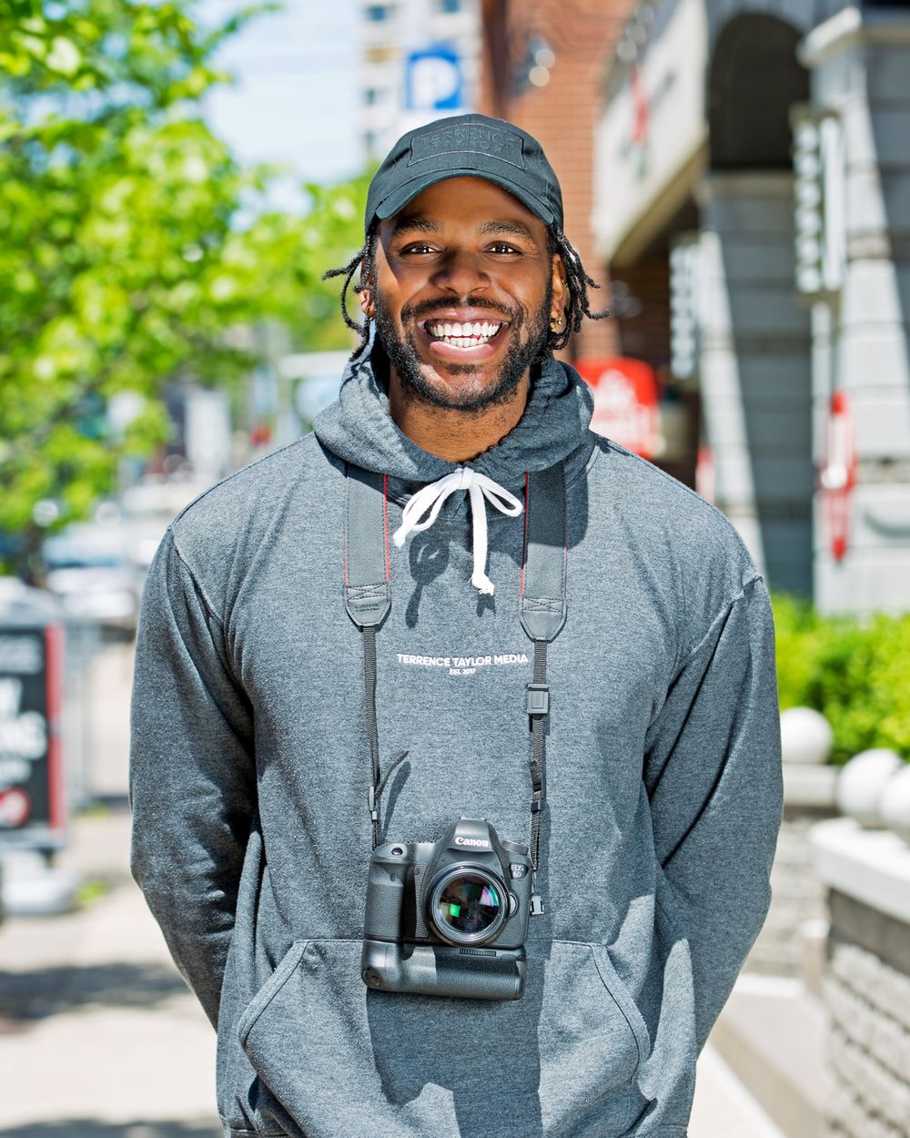 A man is smiling with a camera around his shoulders.