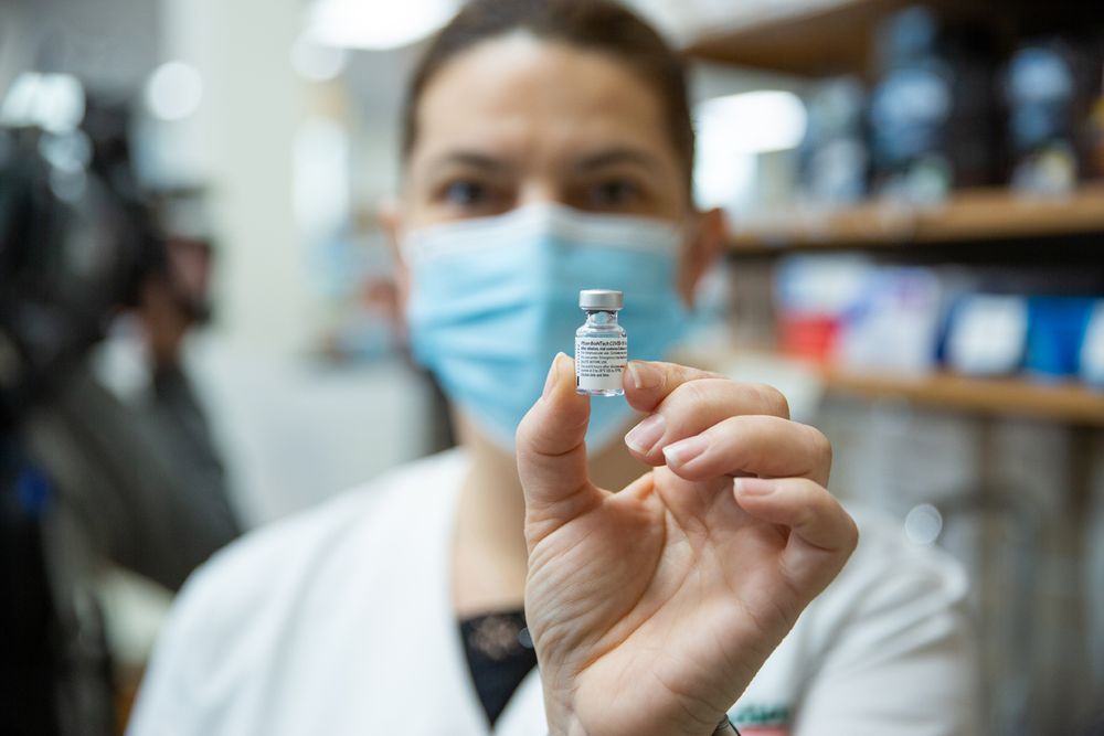 A woman holds up a vial of the COVID-19 Vaccine.