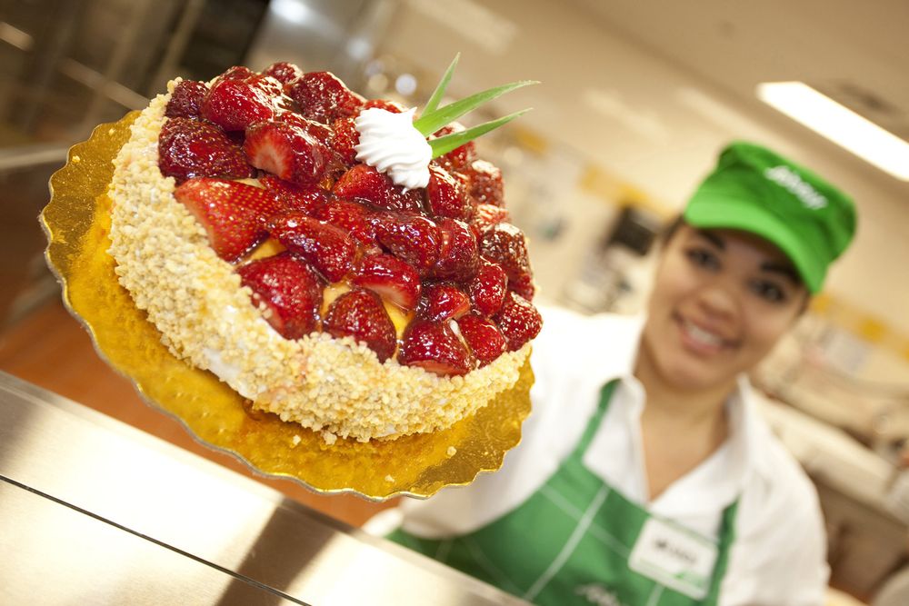 A sobeys baker holds up a strawberry cake.