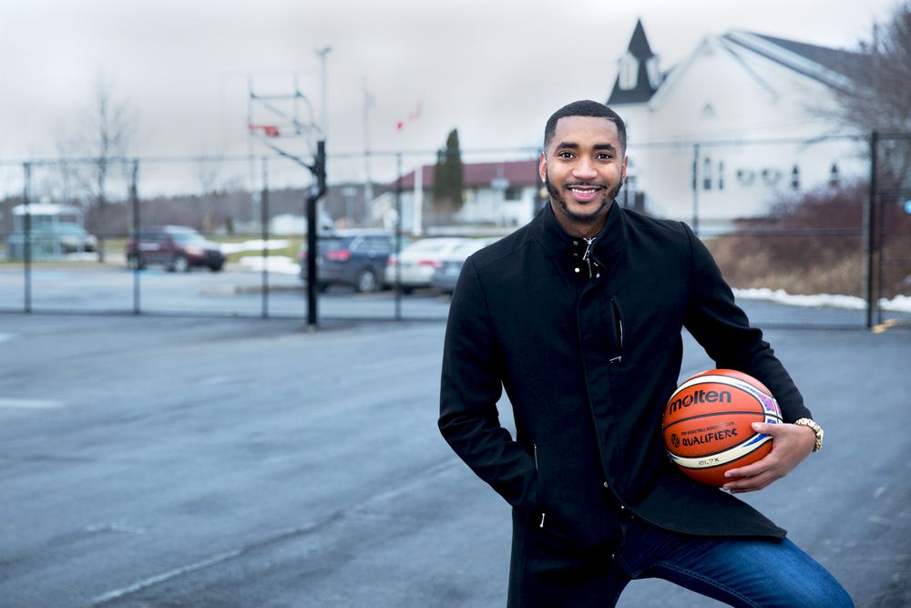 A man poses with a basketball in a basketball court.
