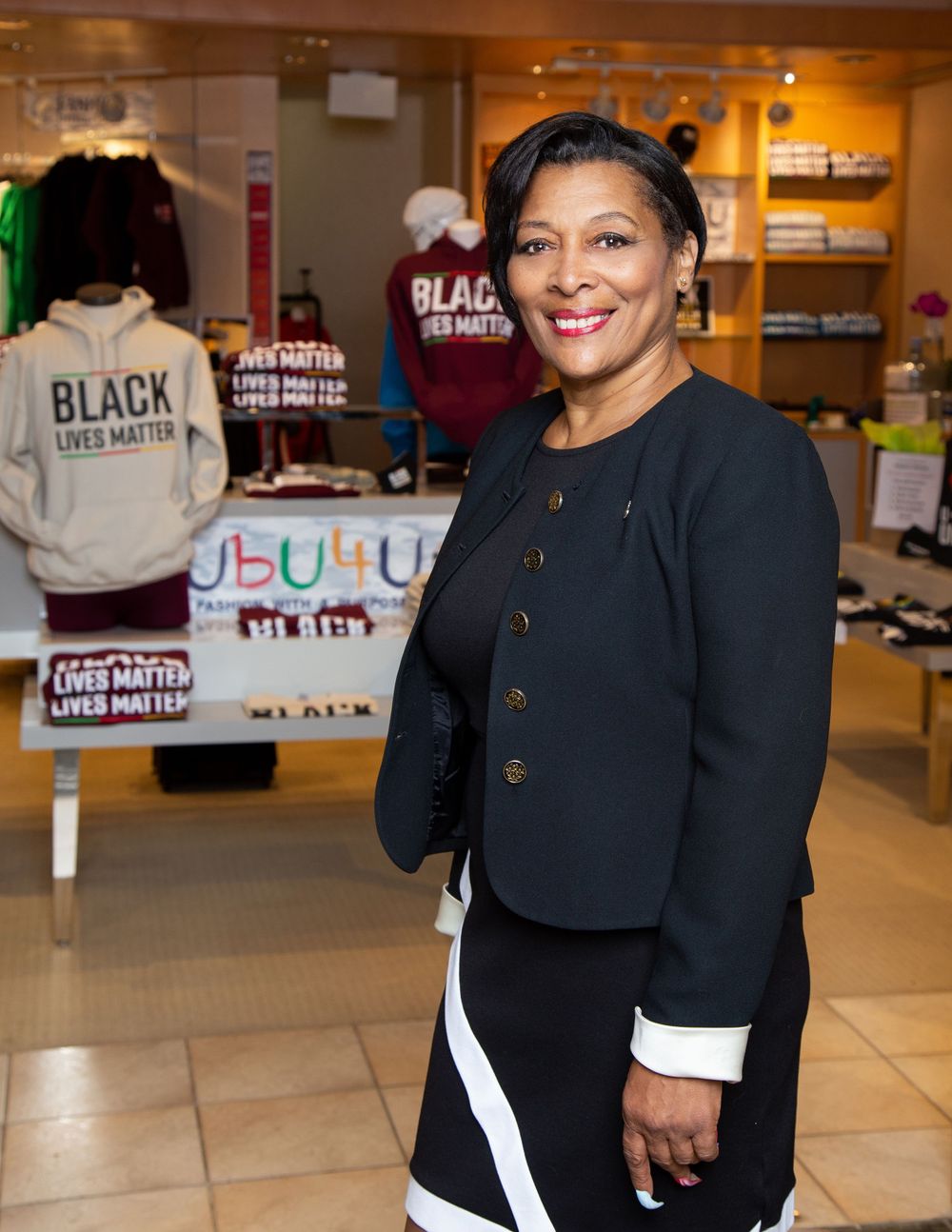 A woman wearing a black hoodie poses infront of a store.