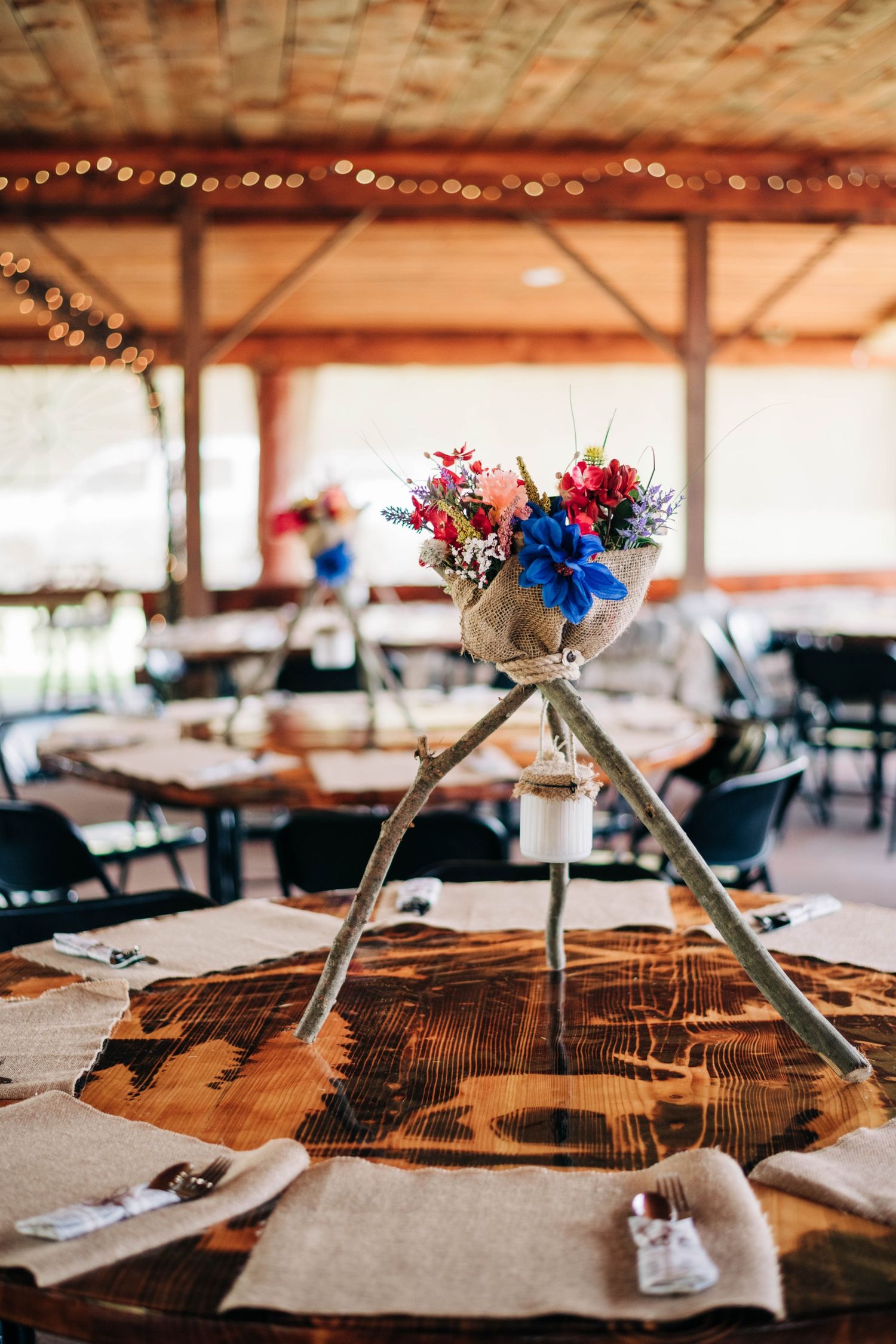 rustic wedding reception centerpiece with blue, pink, and red flowers