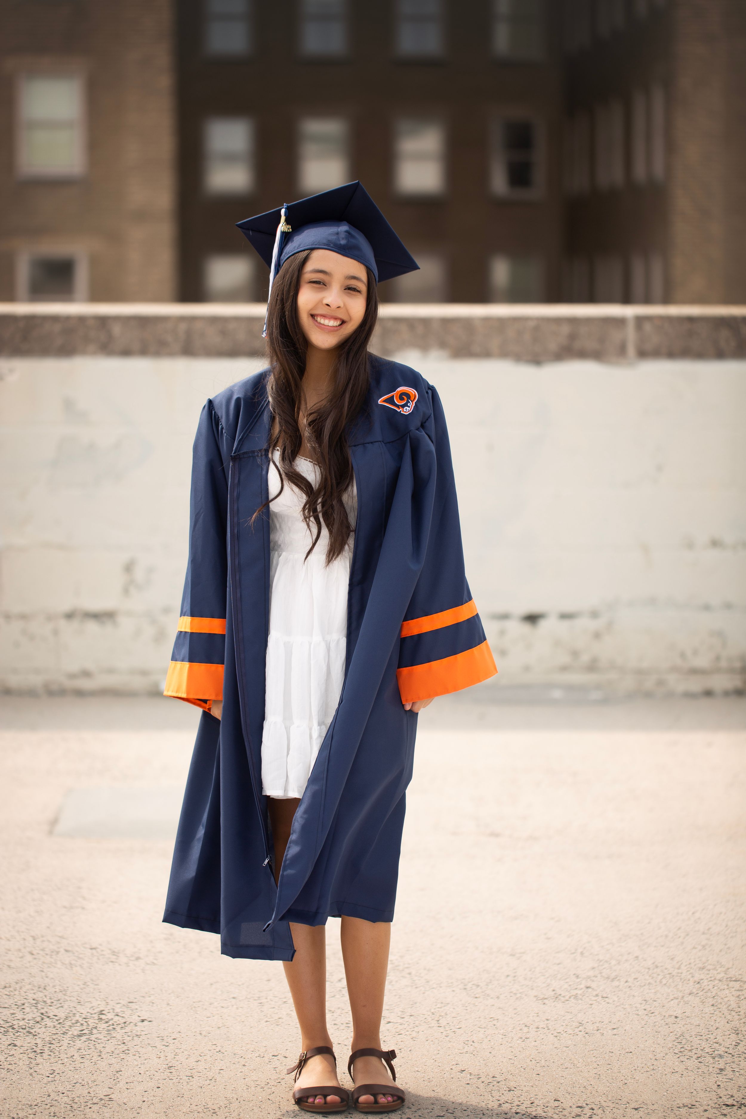 High School Senior girl standing on top of a parking garage in her cap and gown.