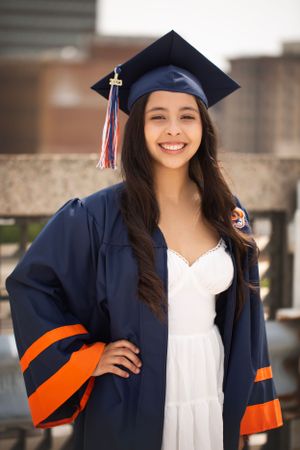 High School Senior girl standing on top of parking deck with her cap and gown on.