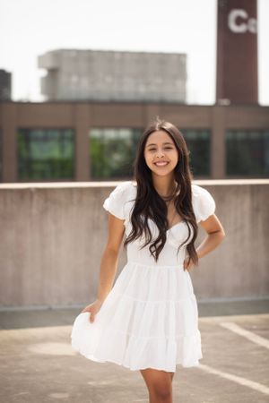 High school senior standing on parking garage twirling her dress.