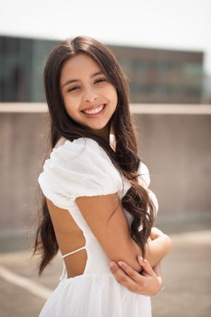 High school senior girl standing on top of parking garage looking at camera.