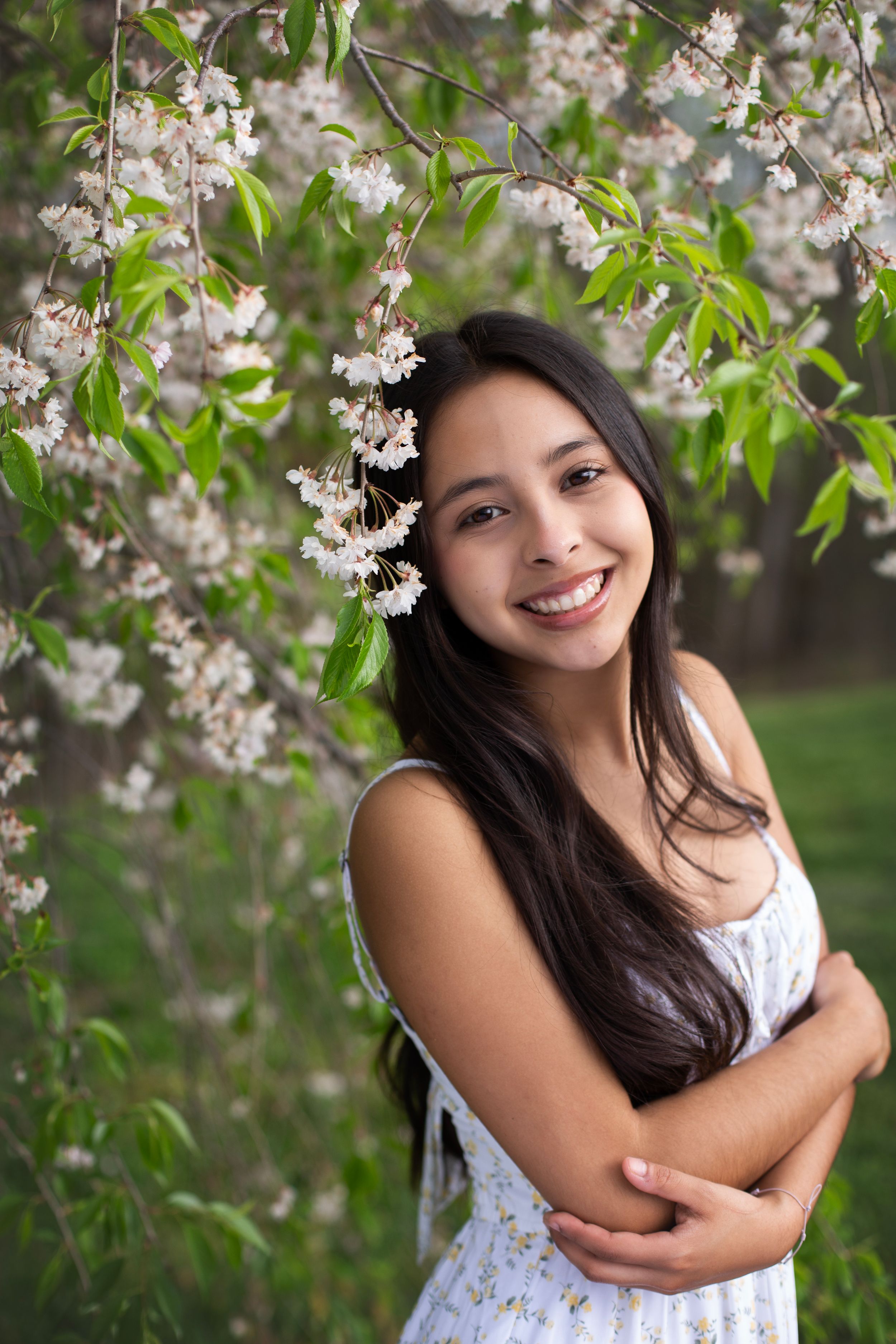 High school senior girl standing just in frame with a flowers surrounding her.