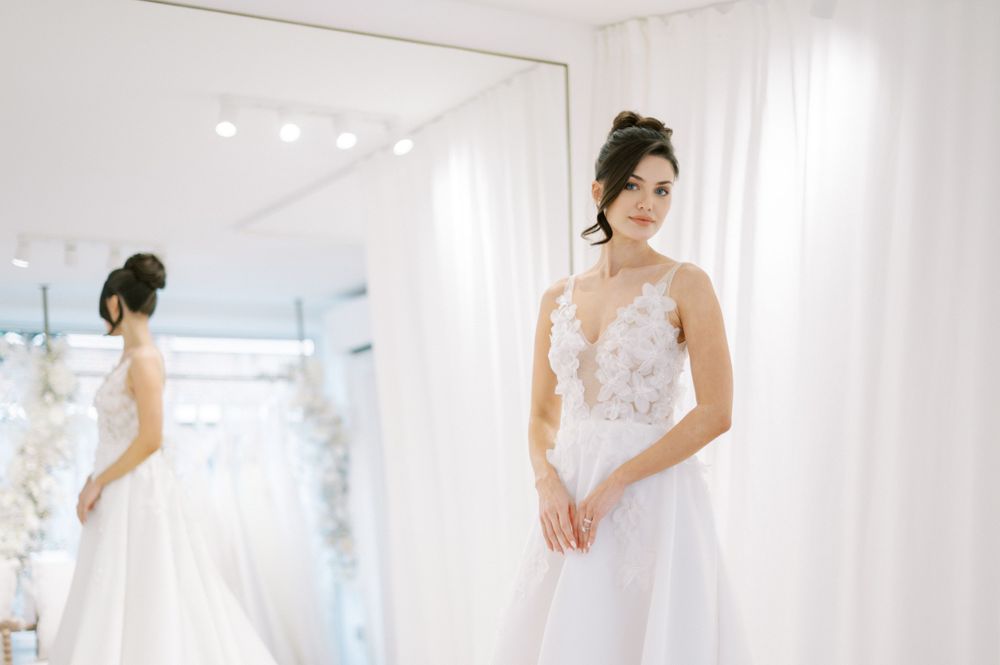 Elegant bridal boutique interior showcasing wedding dresses against white curtains.