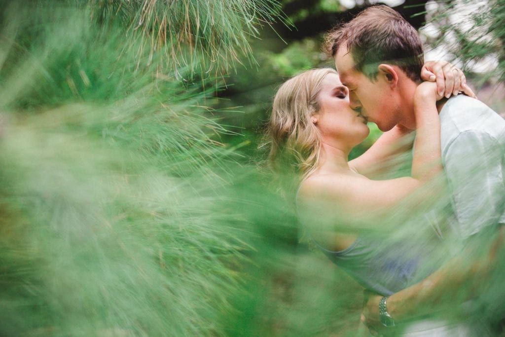 Intimate wedding portraits through green foliage creating natural framing effect.