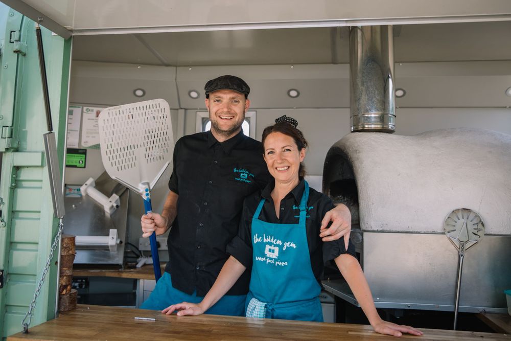 Food truck staff posing together in mobile kitchen.