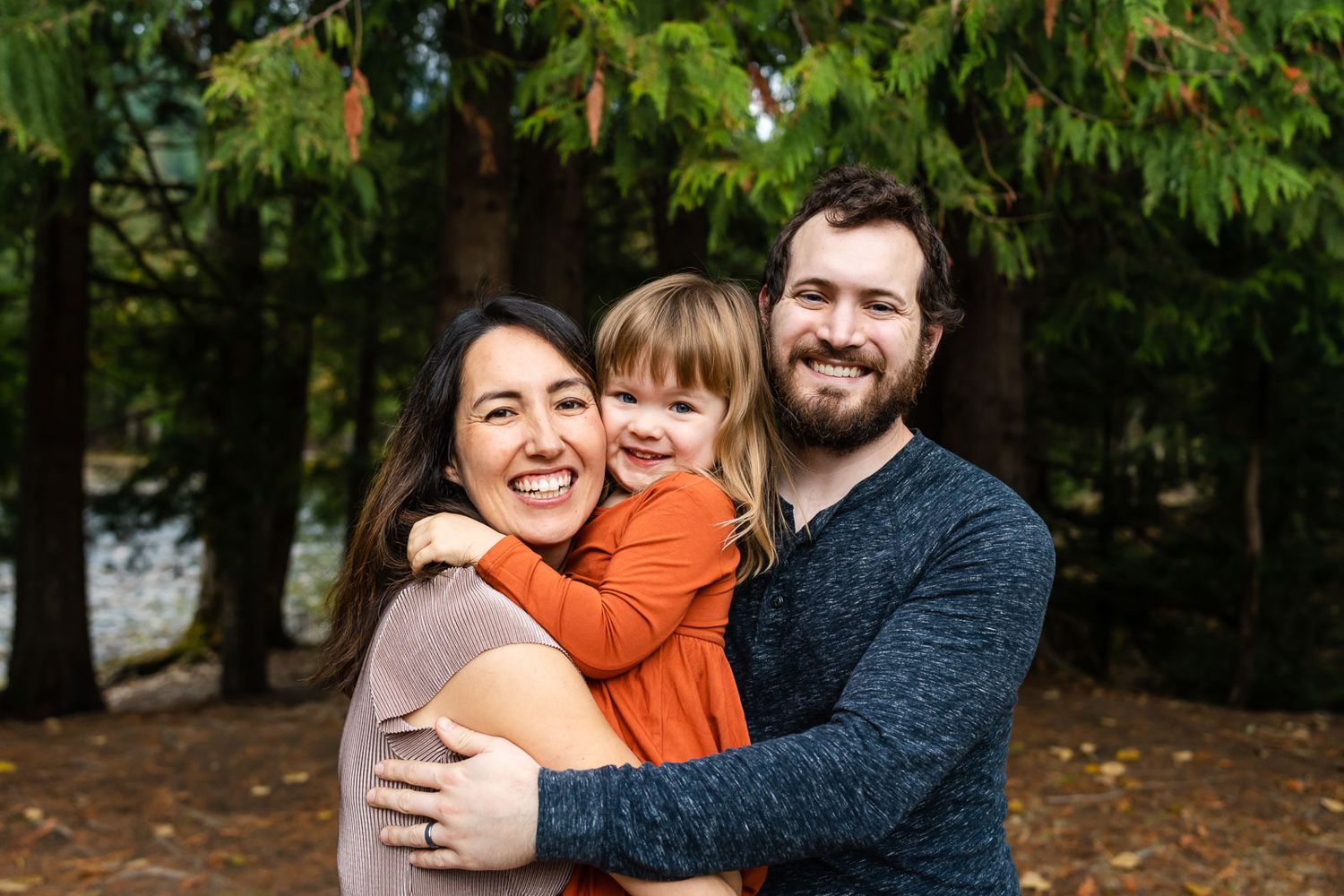 Parents hug their daughter during fall family photos.