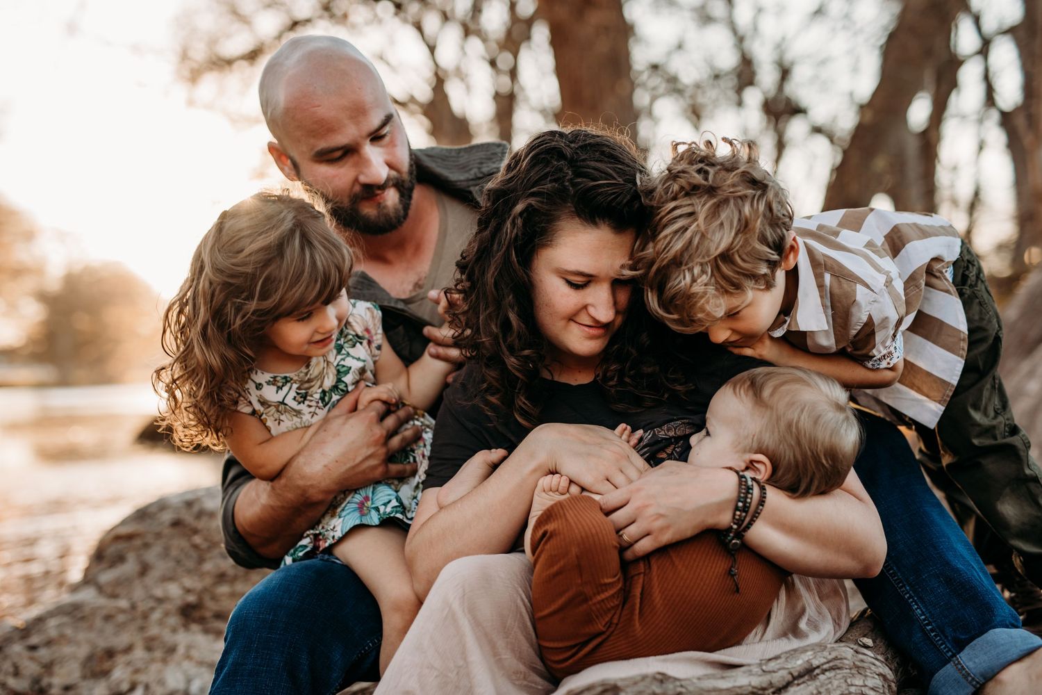 Family cuddling on a rock by the river