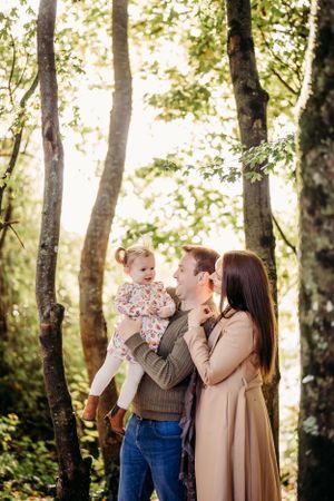 Family sharing tender moment in sunlit forest setting.