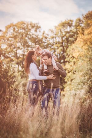 Romantic couple embracing in tall grass during golden hour photoshoot.