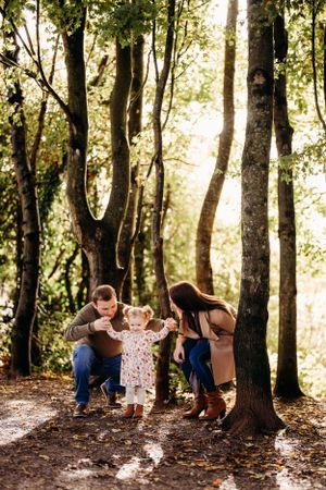 Family playing together on autumn trail surrounded by tall trees.