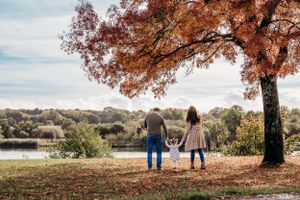 Family admiring lake view under fall foliage on autumn afternoon.