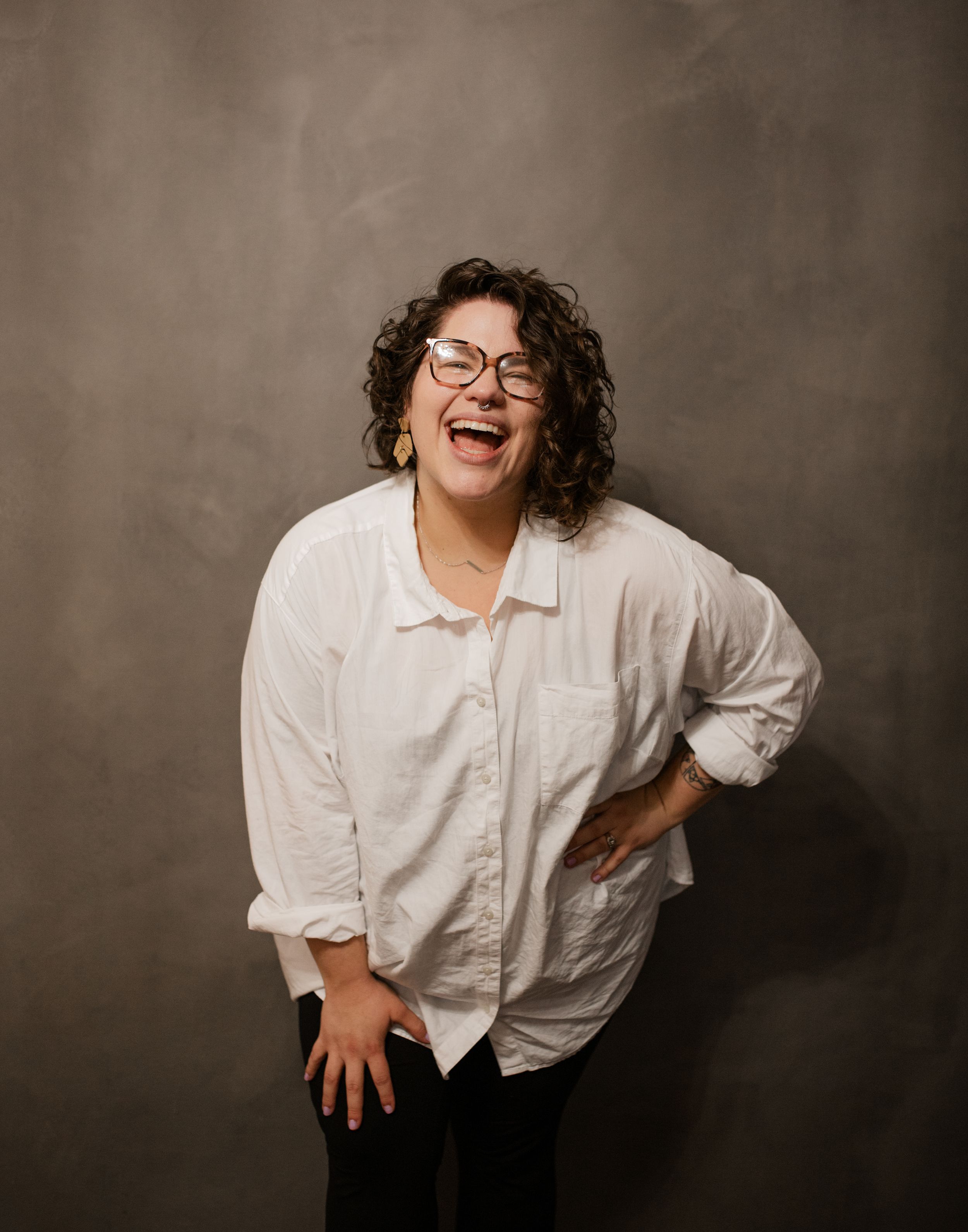 A candid portrait of someone laughing joyfully against a textured brown background.