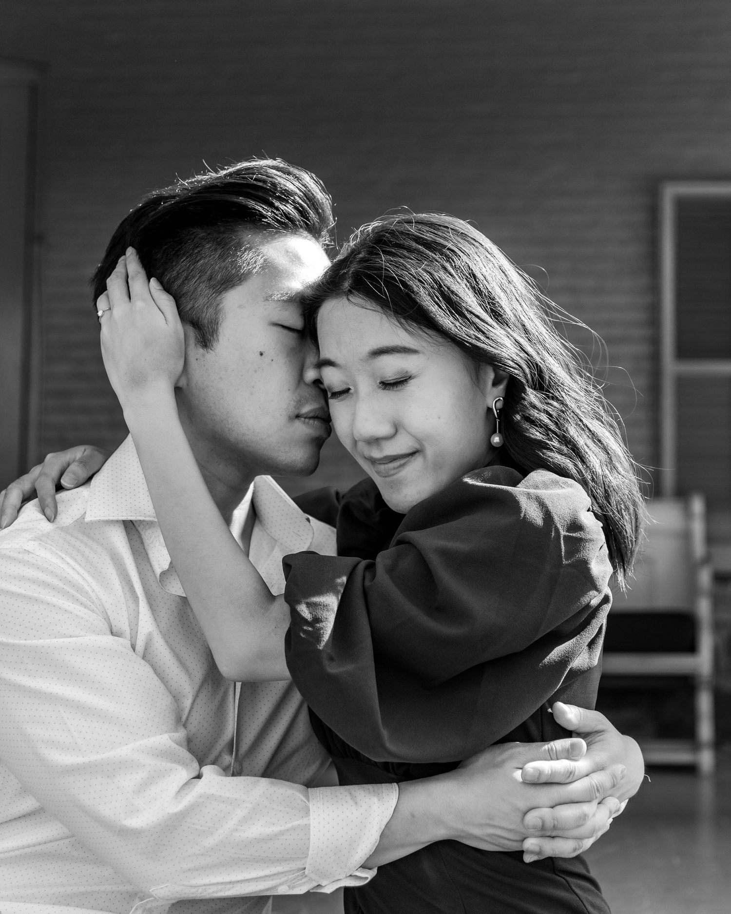 Intimate black and white portrait of couple embracing indoors.