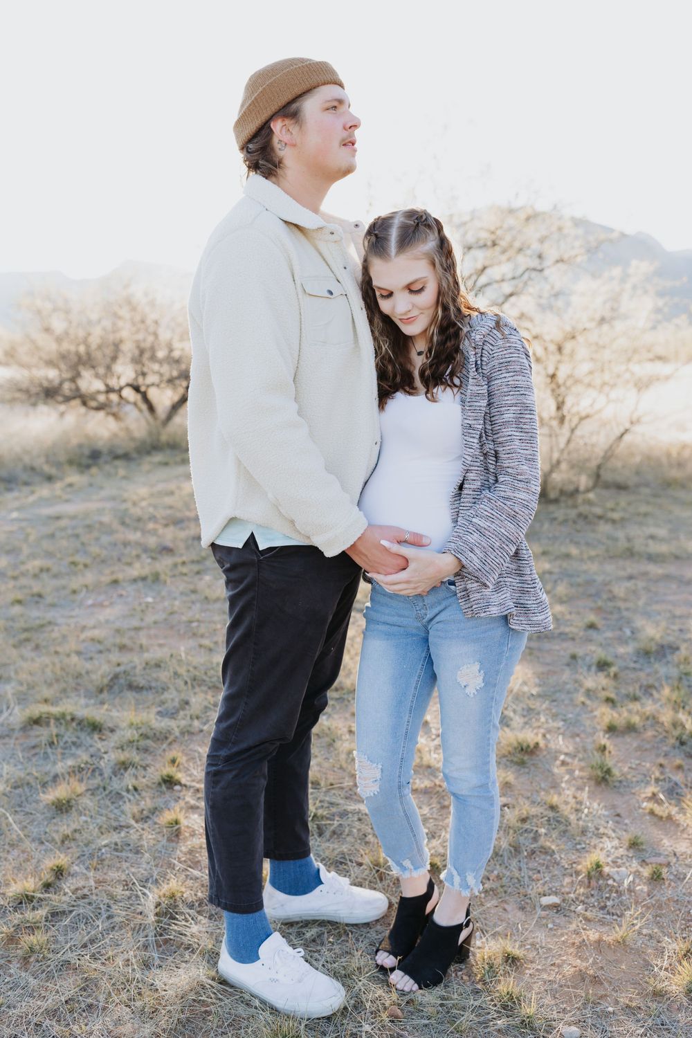 Couple in casual wear sharing intimate moment on hillside during golden hour.