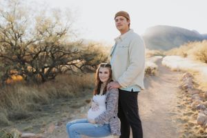 A couple shares a romantic moment on a desert trail at sunset.