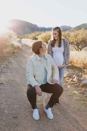 A couple sits close together on a desert path during golden hour.