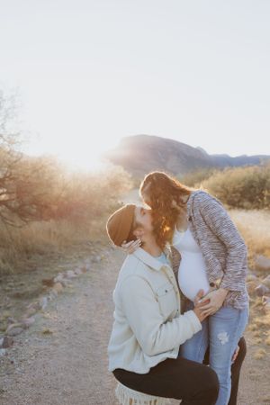An intimate outdoor photoshoot in a desert setting with warm sunlight filtering through.