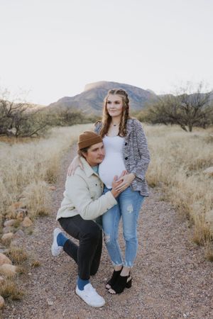 A couple's photoshoot on a desert trail surrounded by mountains and desert brush.