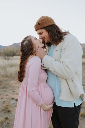 A romantic couple shares an intimate moment in a desert landscape with mountains in the background.