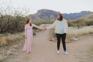 A couple shares a playful moment while walking on a desert path.