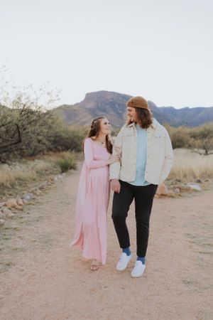 A couple in casual attire strolls together on a desert hiking trail.