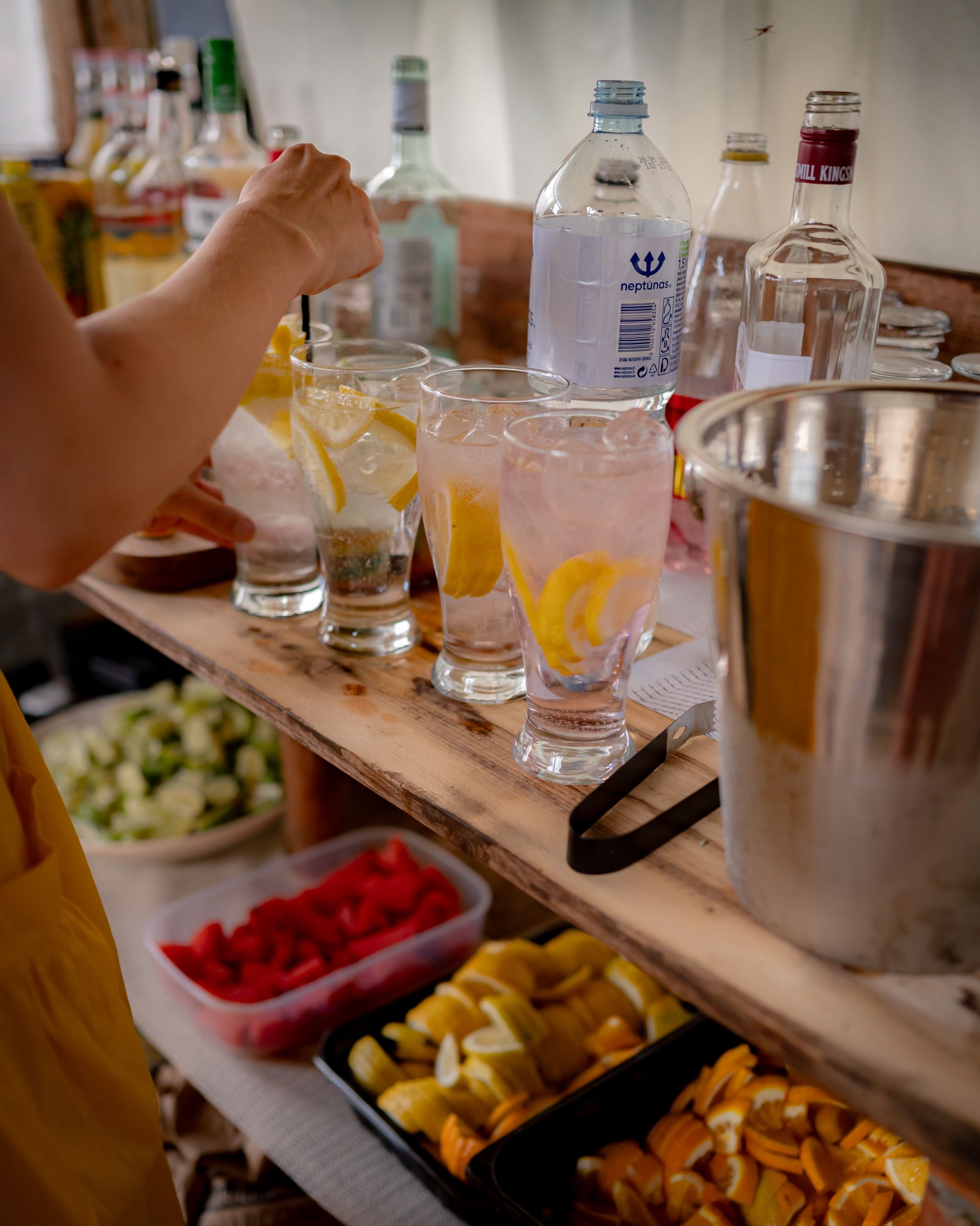 Drink station setup with cocktail ingredients and snacks in small containers.