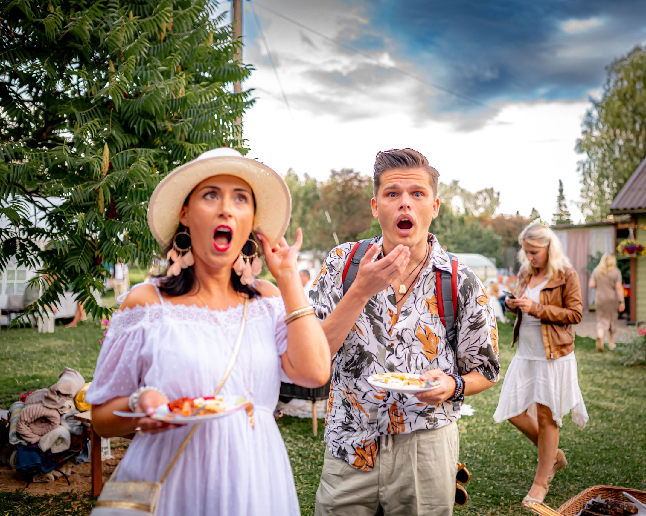 Party guests enjoying appetizers with dramatic expressions at an outdoor garden event.
