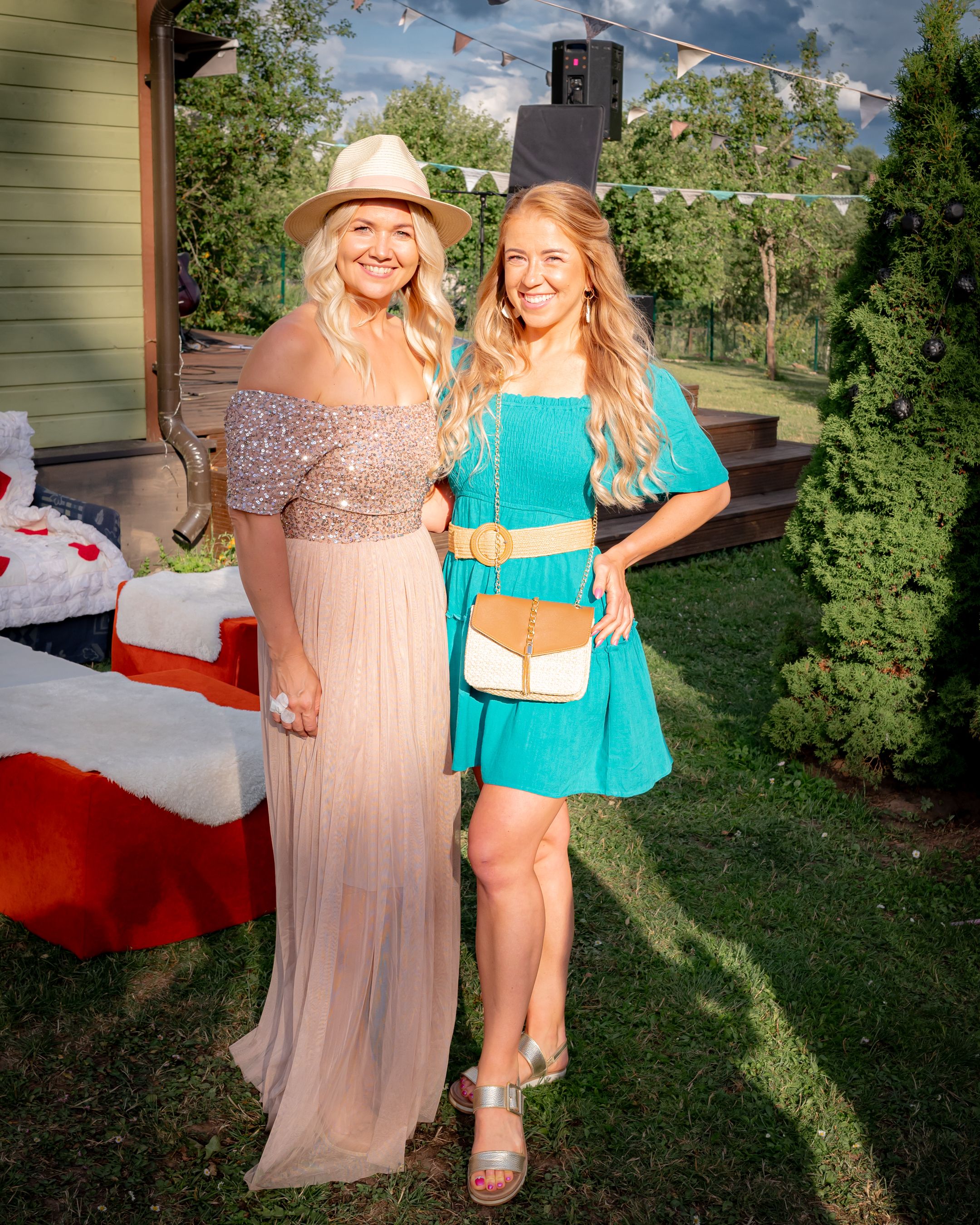 Two guests pose at an outdoor party wearing blush and turquoise summer dresses.