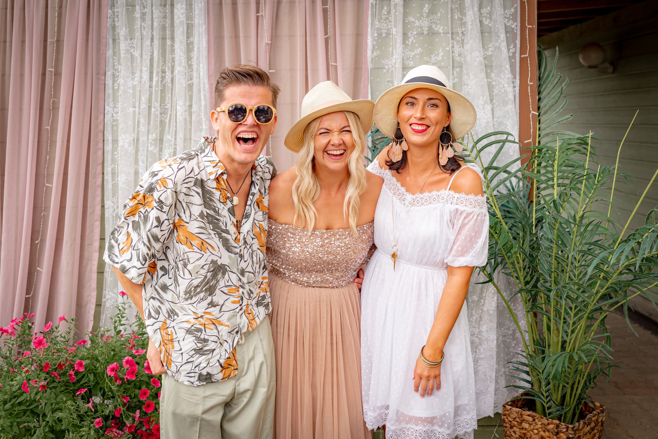 Summer garden party attendees in festive attire posing together against a curtained backdrop.