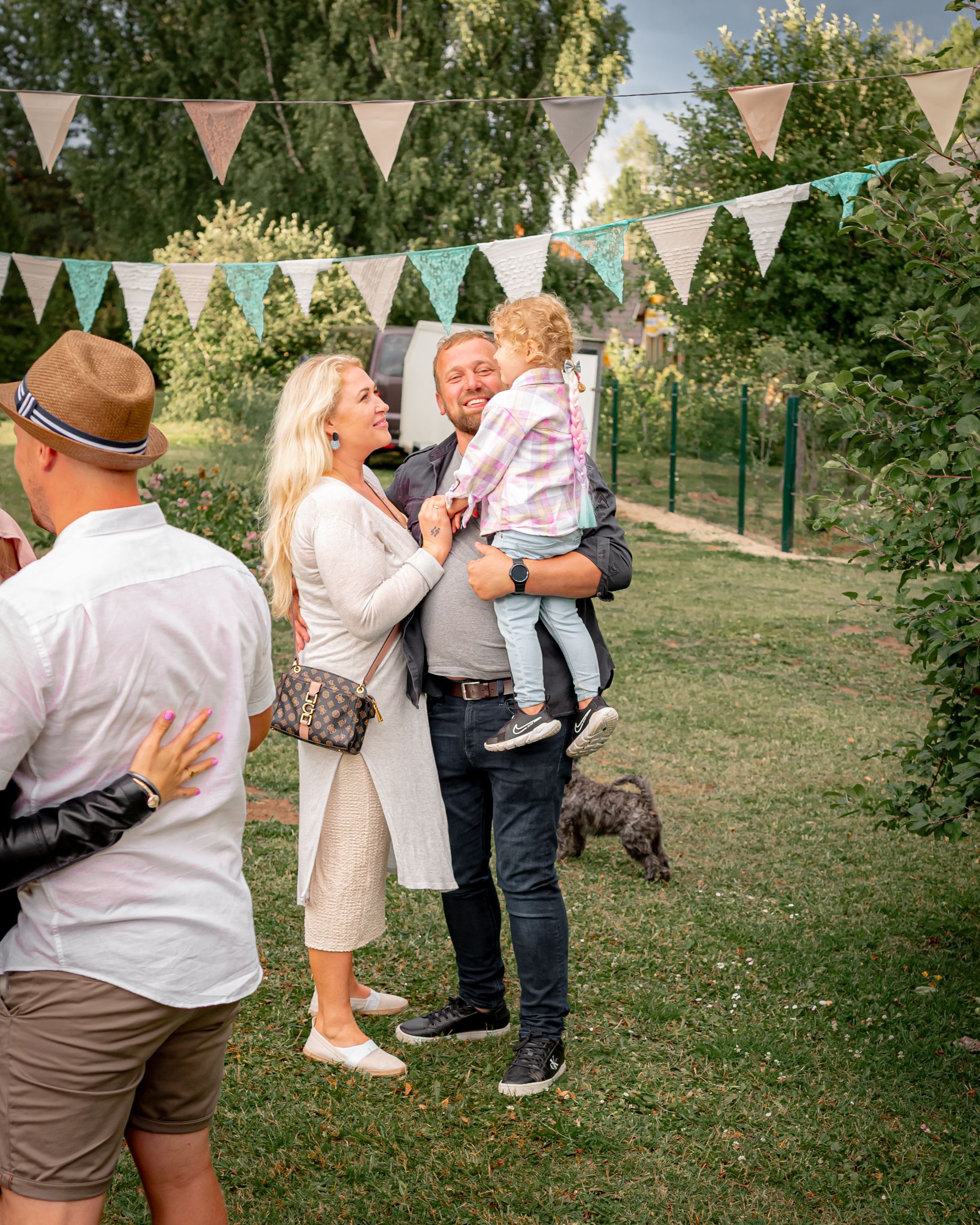 Casual outdoor celebration with guests gathered under pastel bunting flags in a garden setting.
