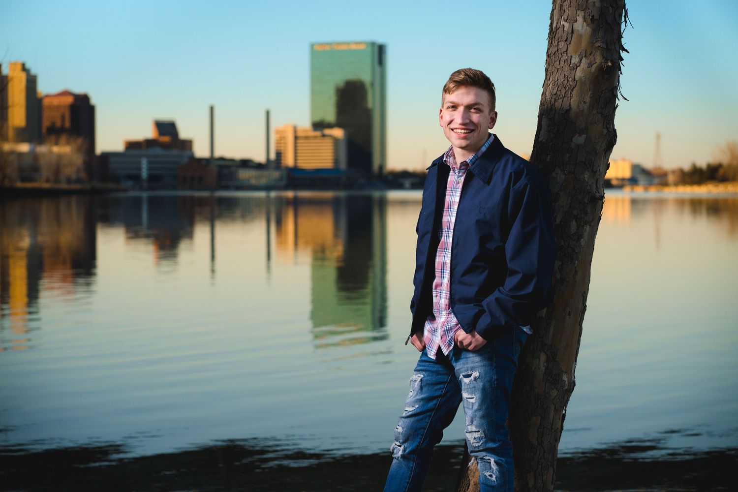 Urban portrait session along waterfront with city skyline at dusk.