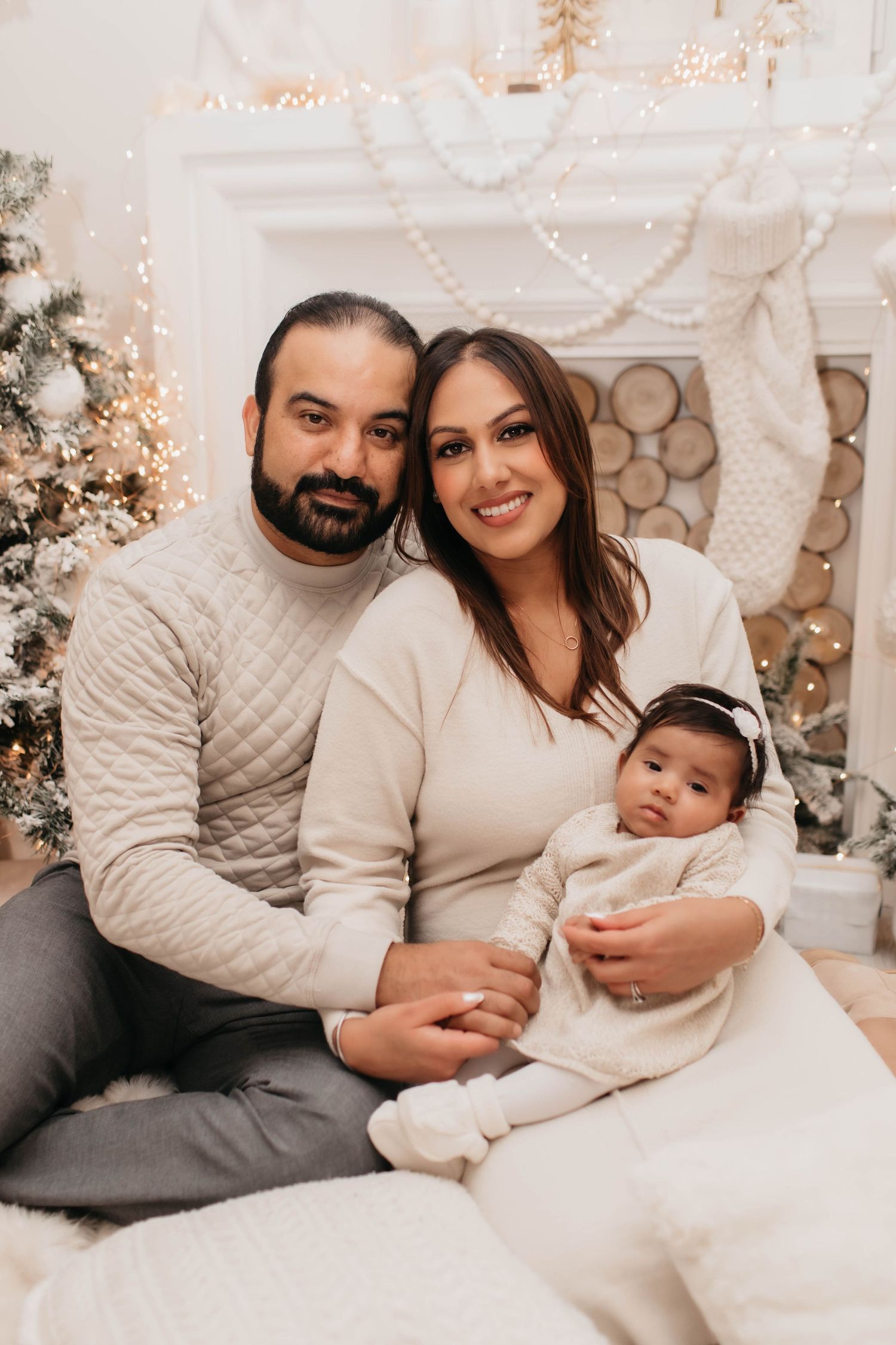 Cozy winter family portrait with Christmas decorations and white knit sweaters.