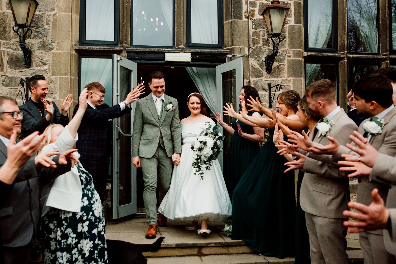 Wedding guests line up to celebrate newlyweds exiting venue.