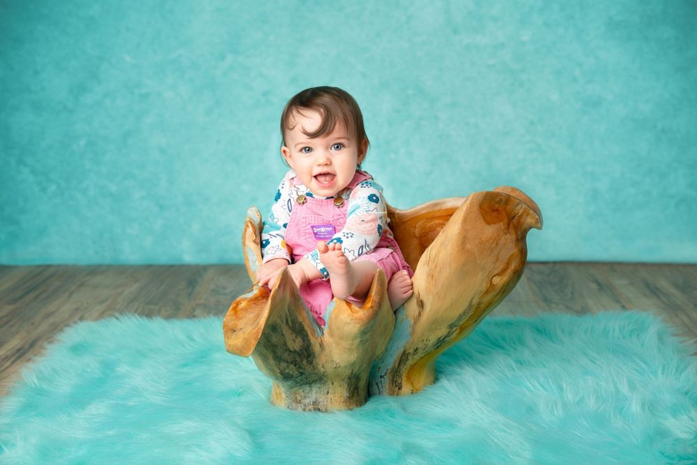 Baby milestone photos with teal backdrop and wooden props.