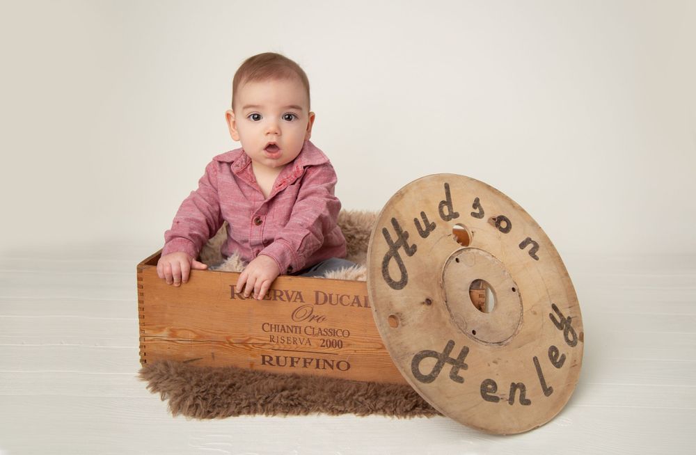 Baby sitting with vintage wooden signage in studio setting.