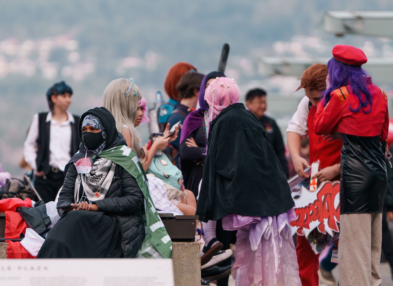 A woman with protest flags resting in front while a group of cosplayers are in the back. Street Photography.