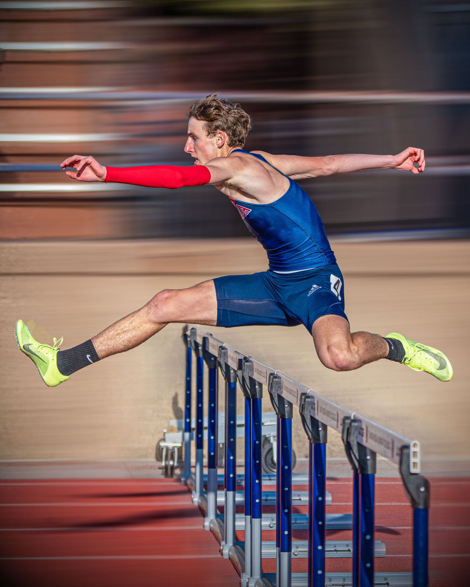 Dynamic motion shot of track athlete leaping over hurdles during competition.
