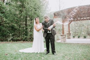 Bride and groom celebrate with a champagne bottle pop at their outdoor wedding reception.