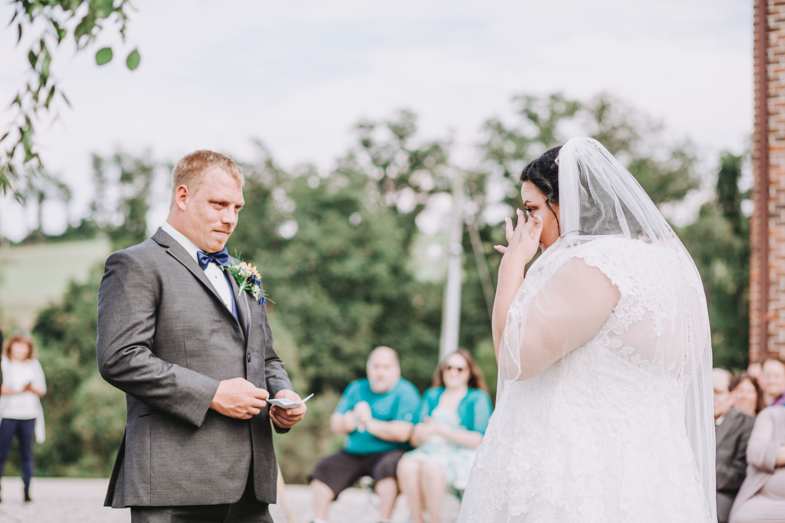 Groom reads heartfelt wedding vows to his emotional bride during an outdoor wedding ceremony.