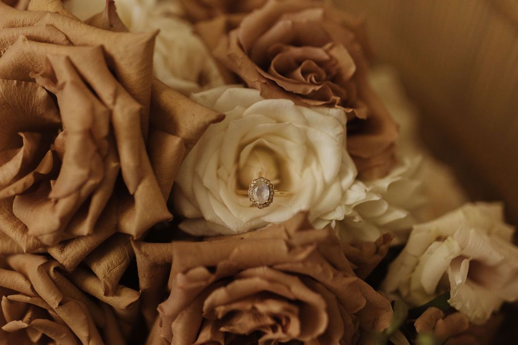 bouquet of neutral coloured wedding flowers with marquis shaped ring in a rose