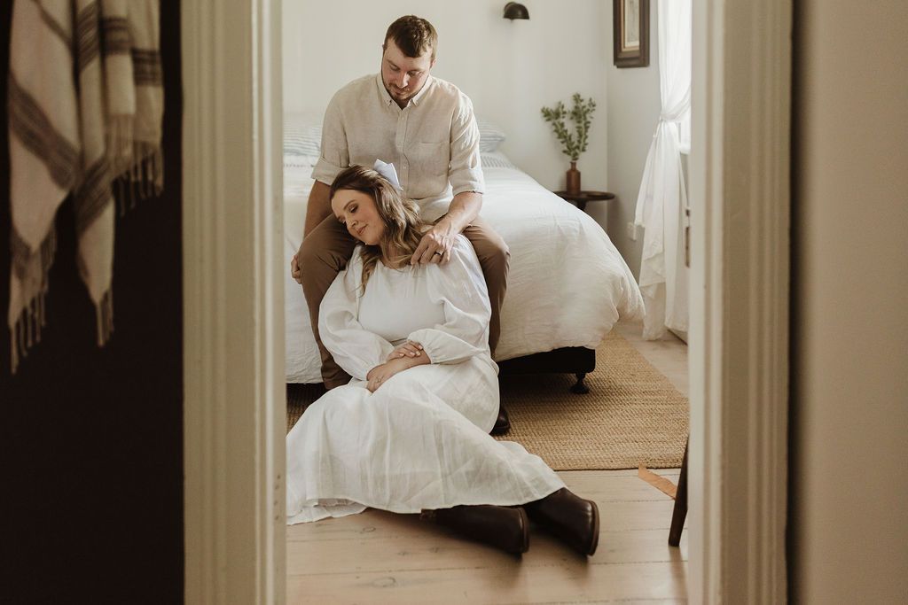 groom sitting on bed of dubbo cottage, bride resting on his leg while sitting on ground