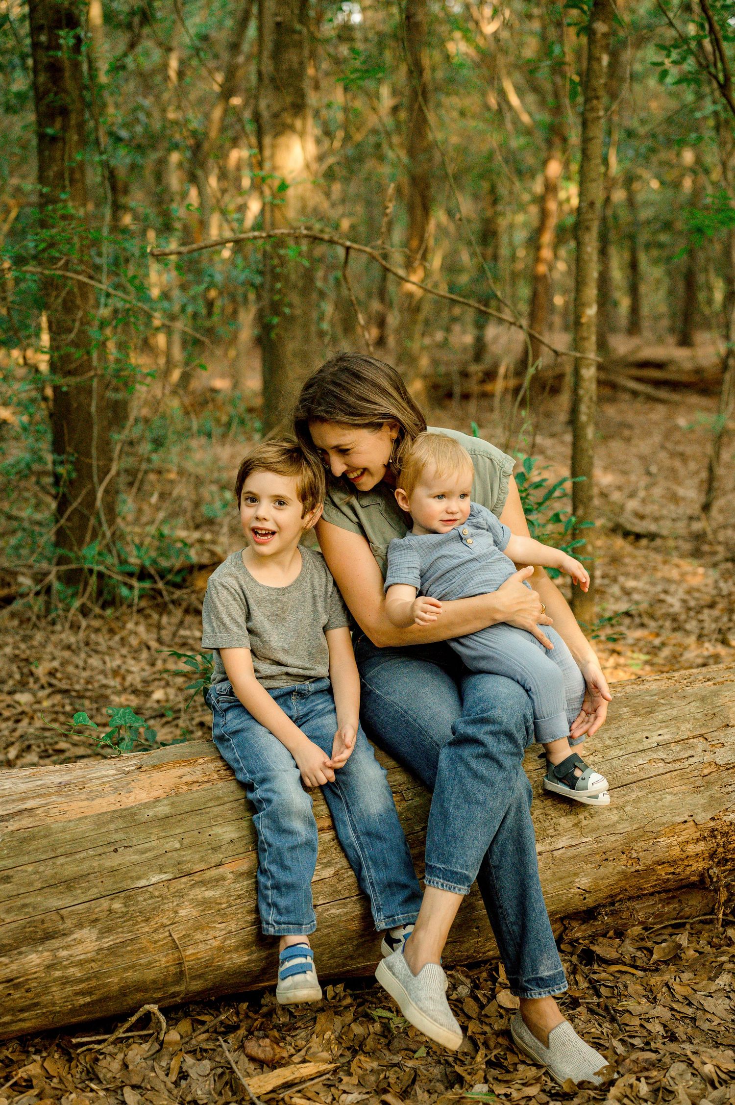 A casual family moment sitting together on a fallen log in the woods.
