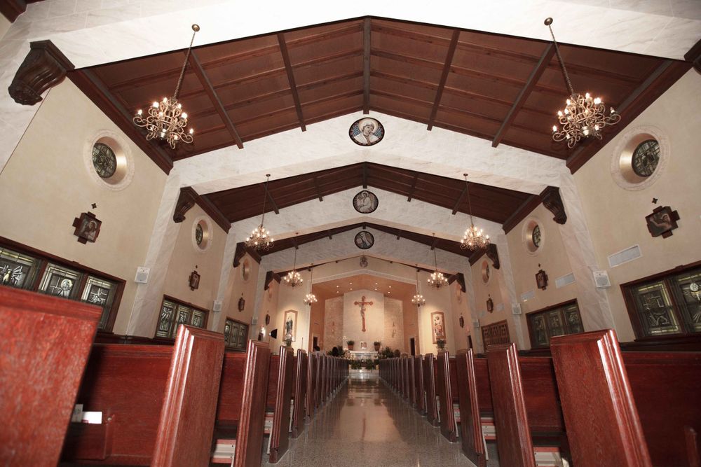 Long hallway with a wooden vaulted ceiling, red pillars and white walls in a historic interior space.