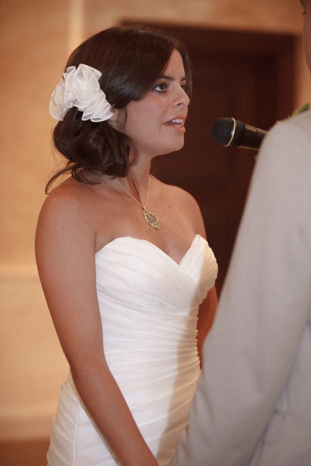 A person in a white wedding dress smiles during an indoor celebration event.